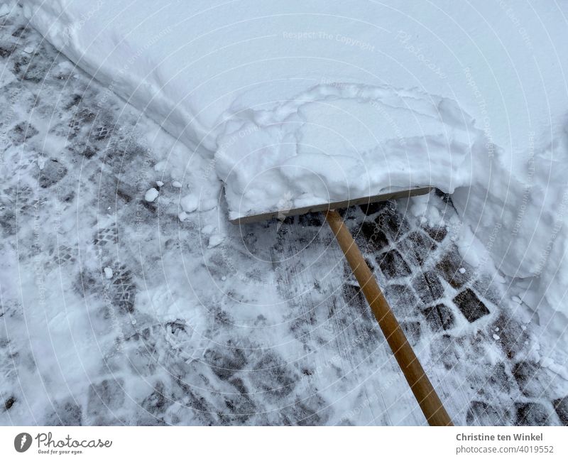 Snow shovel, lots of snow and cobblestones Winter snow shovel clear snow Cobblestones Bird's-eye view Cold Winter maintenance program Snow layer Lanes & trails