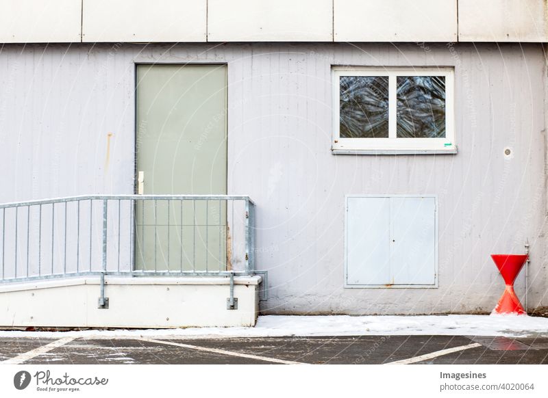 Smoking area.  Facade and ashtray next to the door outside a building. Solitary outdoor area with red ashtray for smokers to take a cigarette break in front of a residential building.