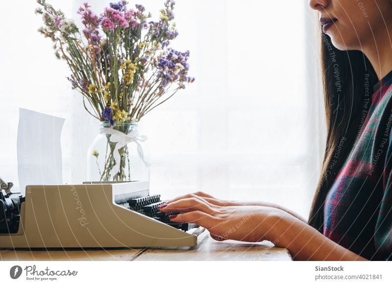 Young woman typing on a vintage typewriter aged antique author background equipment girl hands isolated journalism journalist letter machine message metal