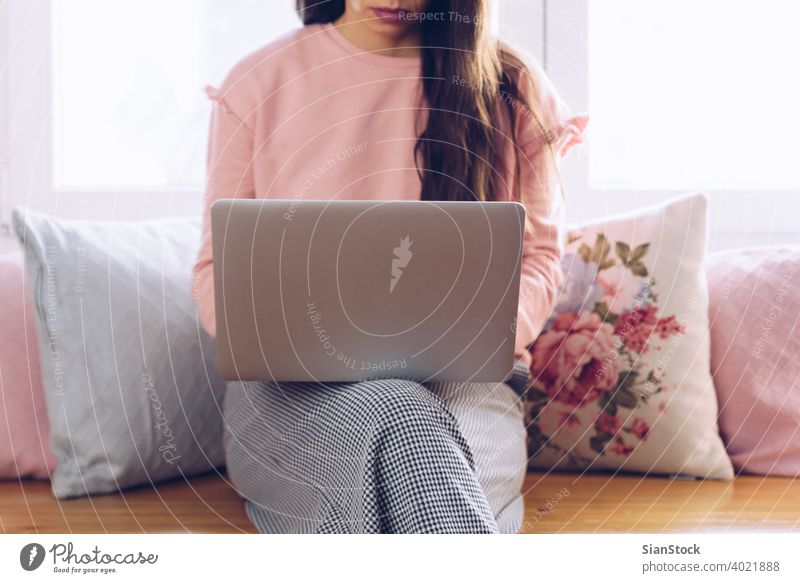 Young woman sitting on her sofa and working at her home. studying pillow carpet interior beautiful window light morning portrait room looking adult internet