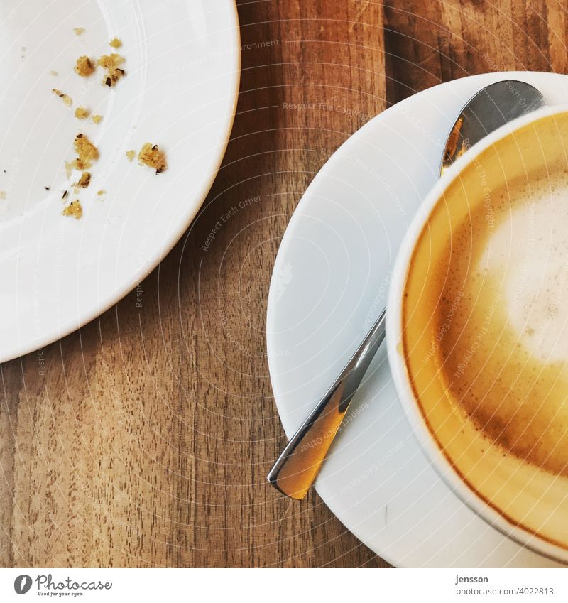 Plate with crumbs and a half full cup of latte Coffee Coffee break Coffee cup To have a coffee Edge of a plate Spoon White Wood Wooden table Foam Empty Eaten