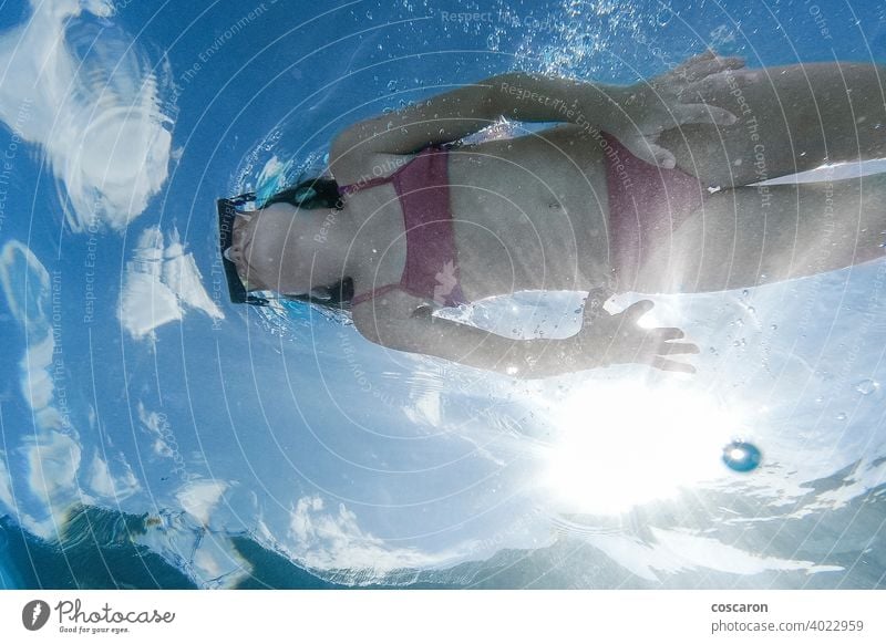 Little girl diving in a pool. View from below. active beautiful beneath bikini blue caucasian child childhood cute dive enjoyment face fun goggles healthy kid