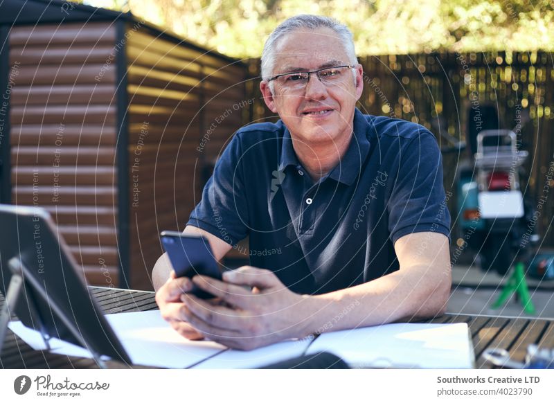 Small business owner working on laptop with workshop in background small small business owner caucasian male man 60's hobby hobbyists candid authentic people