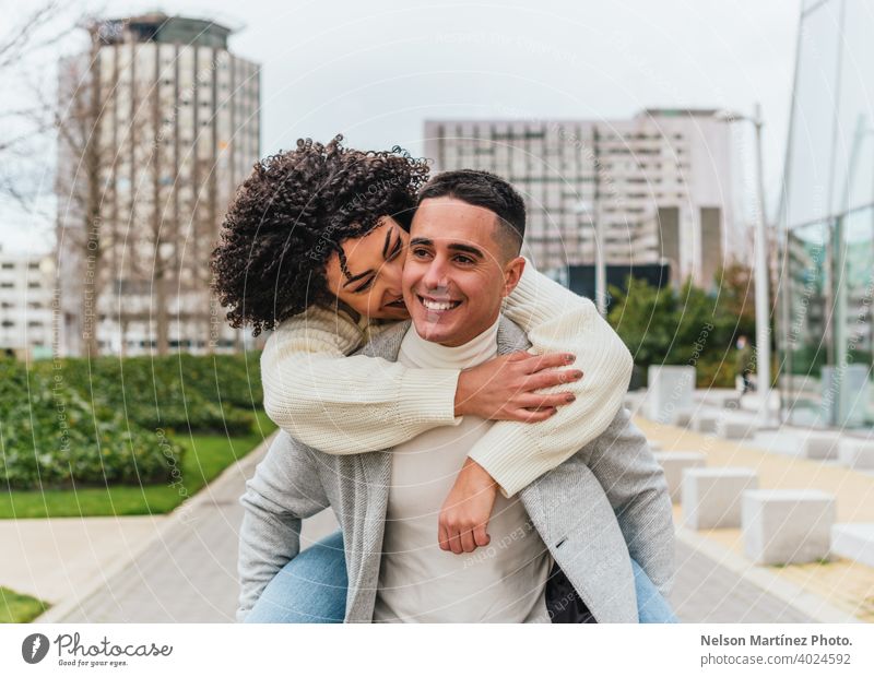 Shallow focus of a young smiling man carrying his girlfriend on his back cheerful couple shallow youth outdoors adult happy woman female people together person