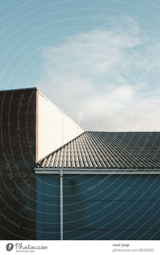 Geometric shapes where a corrugated metal roof meets a sunlit warehouse. Architecture Industry Economy minimalism Minimalistic Blue sky Gray Warehouse