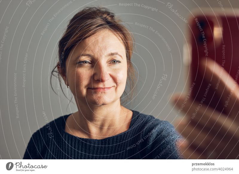 Woman making video call using mobile phone. Talking with relatives. Having fun taking selfie photo using smartphone. Connecting remotely with family person home