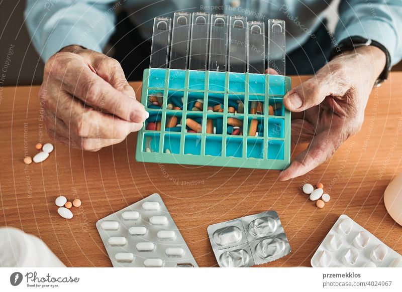 Senior man organizing his medication into pill dispenser. Senior man taking pills from box senior disease patient prescription medical medicine person