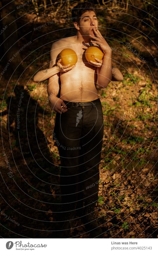 Golden hour in these woods with a wild boy smoking a cigarette. His friend is hiding while holding two melons like a bikini for a male model. This forest is a place where wild adventure happens.