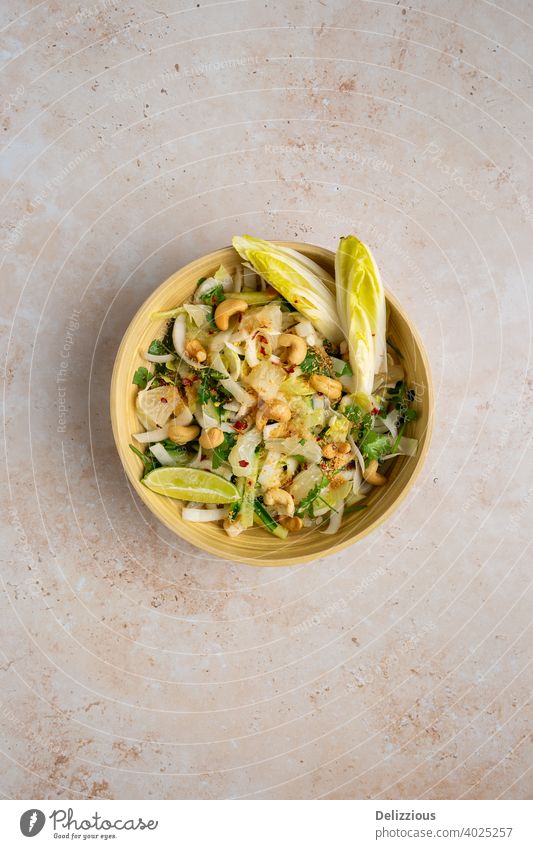 Top down view of a delicious vegan Bali style pomelo salad with chicory, cucumber, cashews, coriander , toasted coconut and chill lime dressing, copy space