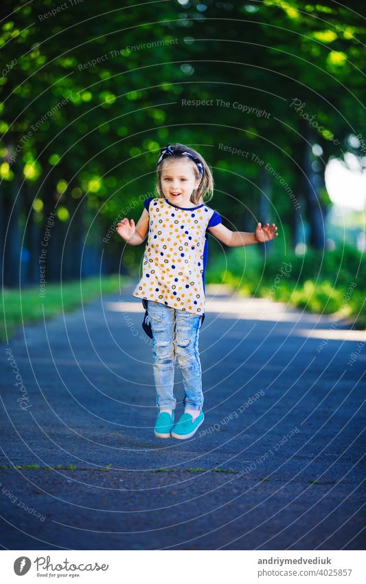 Cute little girl is having fun, jumping and laughing outdoors. happy childhood cute kid cheerful young lifestyle people person happiness park grass adorable