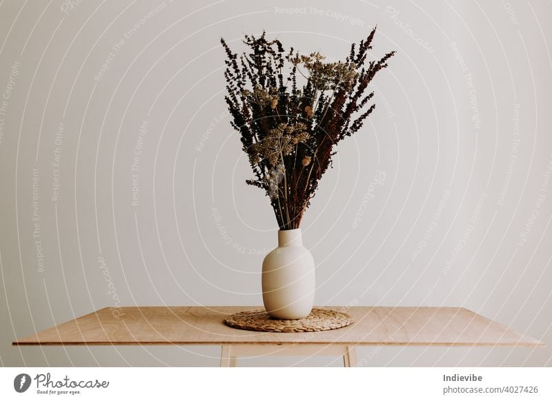 A bunch of wild dried flower in white ceramic vase closeup on brown wooden table. bouquet isolated spring flowers nature decoration blossom floral green