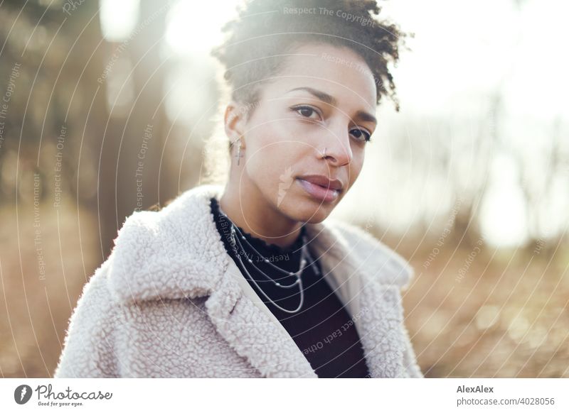 Young woman in fur jacket standing in nature by a lake Woman Athletic Dark-haired Long-haired pretty Strong Graceful naturally Curly Slim Back-light Nature from