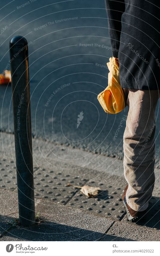 At the roadside Man Street Bollard person Pouch Bag Yellow leg Pants Jacket off corduroy trousers Stand Exterior shot Colour photo Human being Anonymous