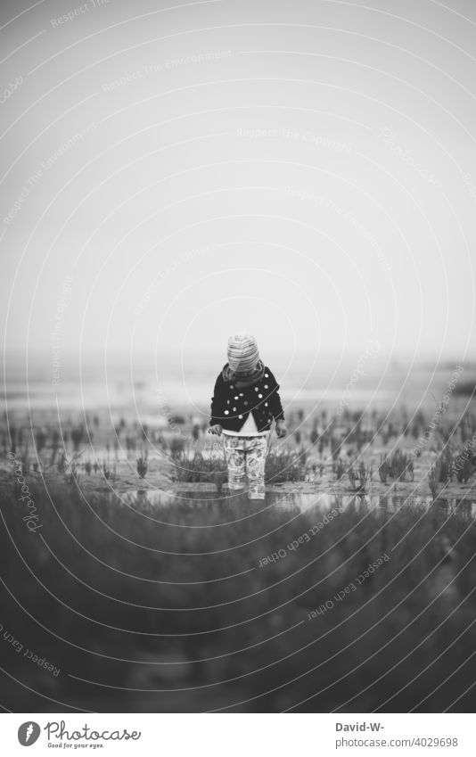 small child standing in the mudflats watching nature Child Mud flats watt explore Ocean by oneself Nature Observe inquisitive North Sea coast Vacation & Travel