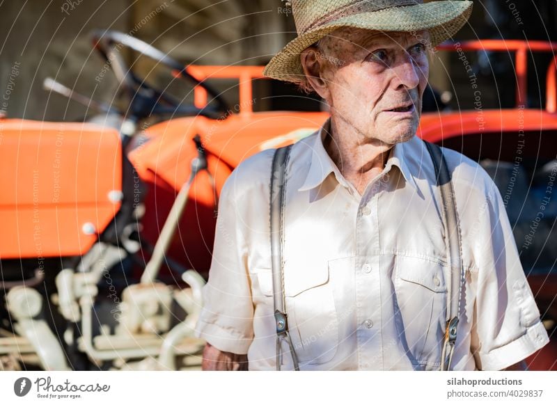 Portrait of very old farmer with straw hat explaining life in front of a red tractor. generation adult aged agriculture auto automobile car caucasian characters