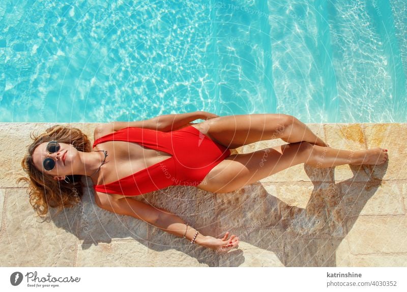 Young woman in red swimsuit relaxing near a pool tropical water one-piece copy space boho lay top view Summer caucasian Fashion alone Happy smile Garden Emotion