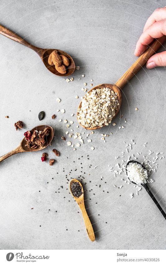 Muesli ingredients on spoons on a rustic background Cereal Ingredients Spoon Hand Breakfast Nutrition Diet Organic Oat flakes Almond sciatic seed coconut flakes