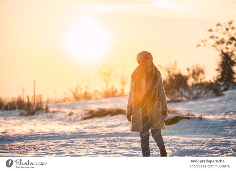 Woman walking on snowy field at sunset winter countryside happy nature season enjoy glad fresh cold cheerful stroll smile sundown recreation lifestyle weather