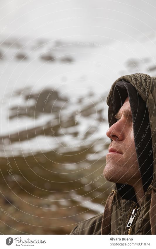 Stock photo of a man wearing camouflage clothing, and trekking in the high mountain of Moncayo in Aragon, Spain, surrounded by huge rocky and snowy hillside.