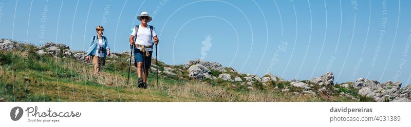 Senior couple practicing trekking outdoors landscape senior mature hikers walking trekking sticks banner web header panoramic panorama countryside nature