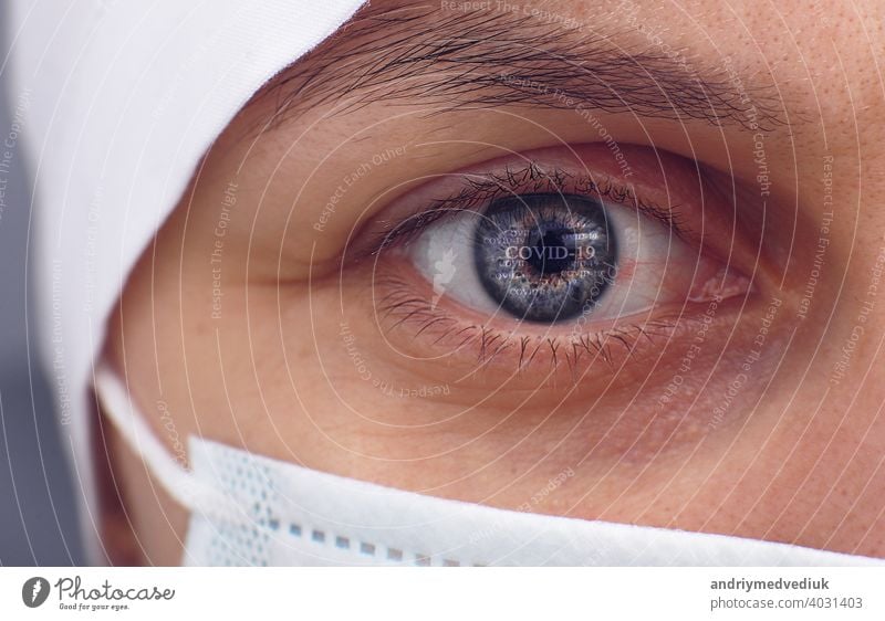 Closeup of irritated red bloodshot stressed eye of female doctor at coronavirus covid-19. Regret, anxiety and despair. Pandemic and virus epidemic. Concept of health, disease and treatment.