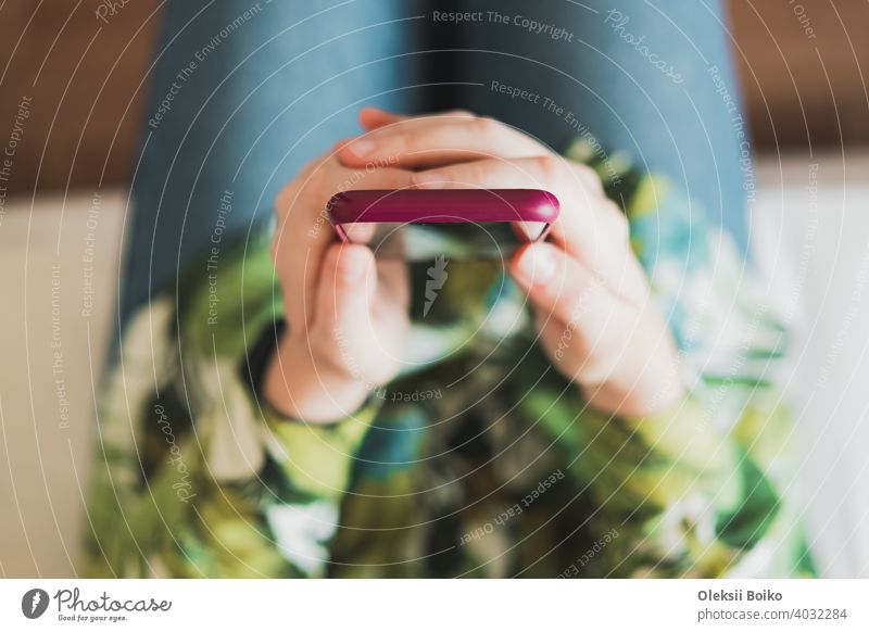 Mobile phone in woman's hands, shot from above with thin depth of field. Female person holding a smartphone in hands background blank browsing cell phone