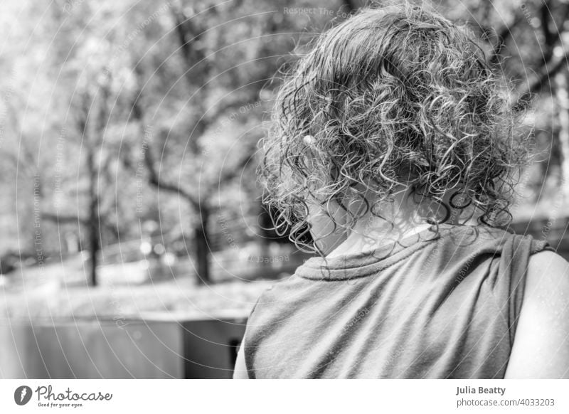 Young girl with wet curly hair looking off to side; outdoor playground in summer portrait young curls natural untamed wild damp clumps wavy beauty beautiful