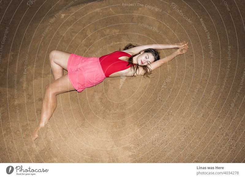 Gorgeous brunette model feeling cozy and relaxed on this hill of sand. Dressed in pink shorts and a red swimsuit, that can’t hide her sexy curves. The perfection of wild summer nights.