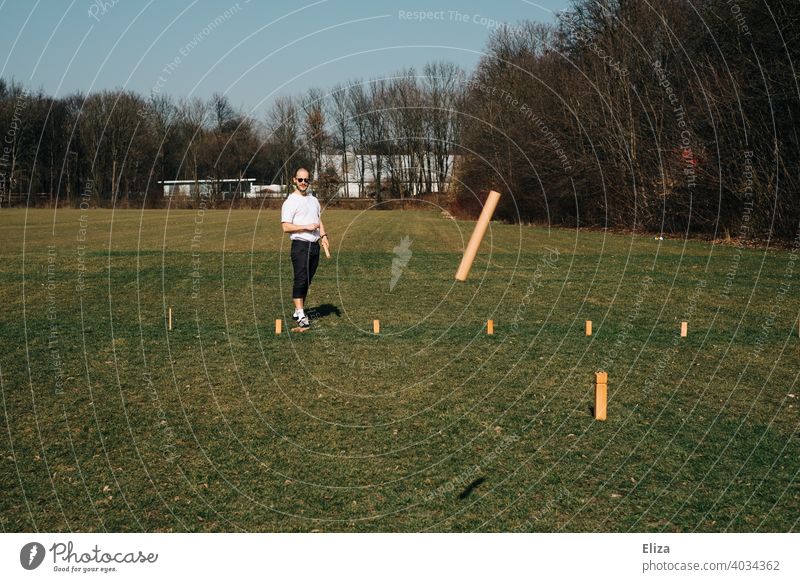 A man playing Viking chess/Kubb outside on the meadow Viking Chess cubb Playing Man Throw game activity free time active Spring Summer Sun Meadow Outdoors