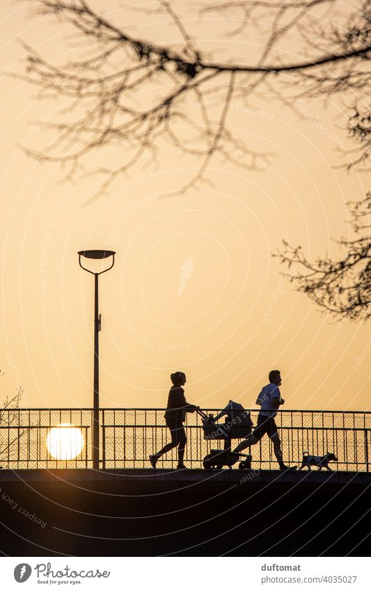 Backlight shot of family at sunset Back-light Family Silhouette Sunset Jogging Walking Sahara sand Sports Fitness Movement Baby carriage Sunlight Healthy