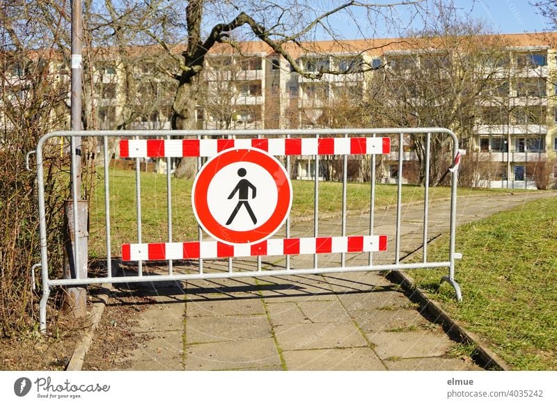 "Passage prohibited" - sign and barrier fence block the flagstone path through the green area towards the modern apartment buildings / Living in the green / VZ 259