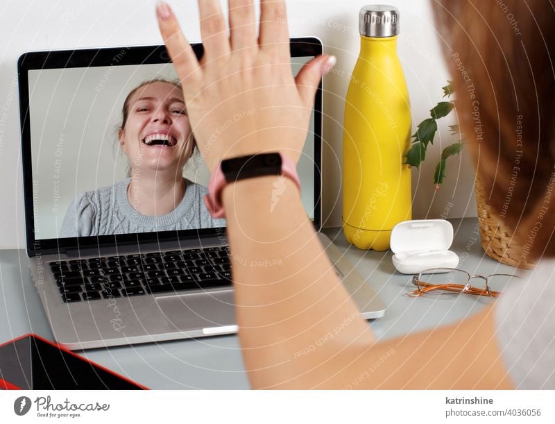 Two friends drinking wine while having a video call women laptop isolation Social distancing videocall smile laugh grey person bottle table desk glasses hand