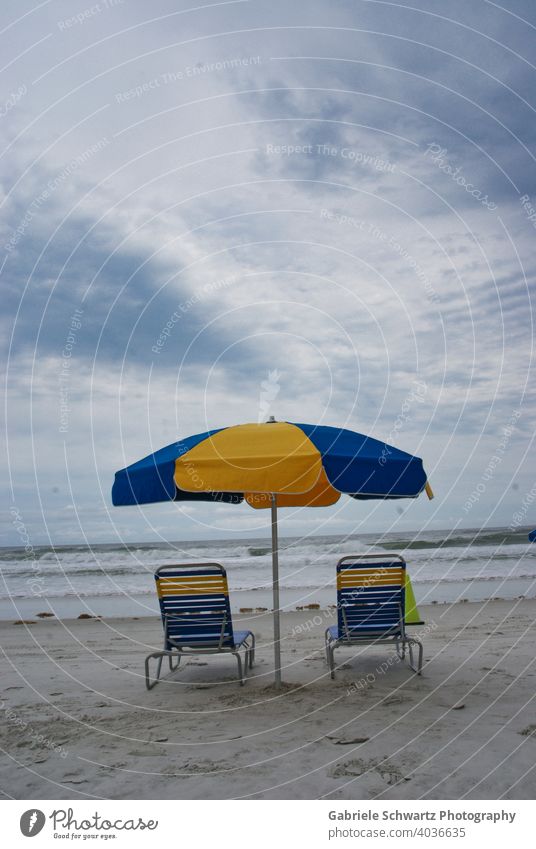 Lonely deck chairs by the sea Deckchair Ocean Beach Empty Waves Swell White crest Sand Sandy beach Stripe Striped Blue Yellow Sunshade Seaweed Clouds