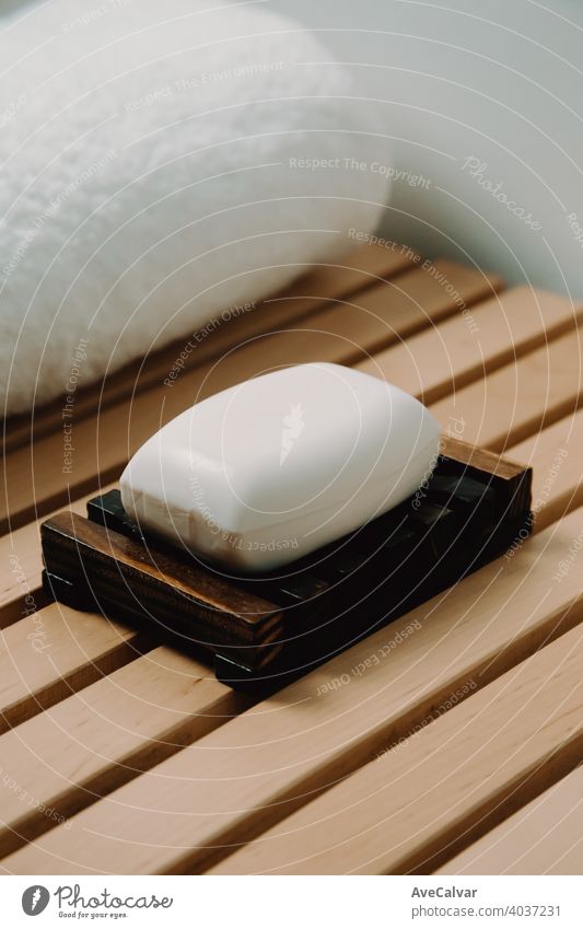 A hard soap over a wooden soap dish in a bathroom with a spa concept relax shower clean wash background white hygiene closeup texture health care water beauty