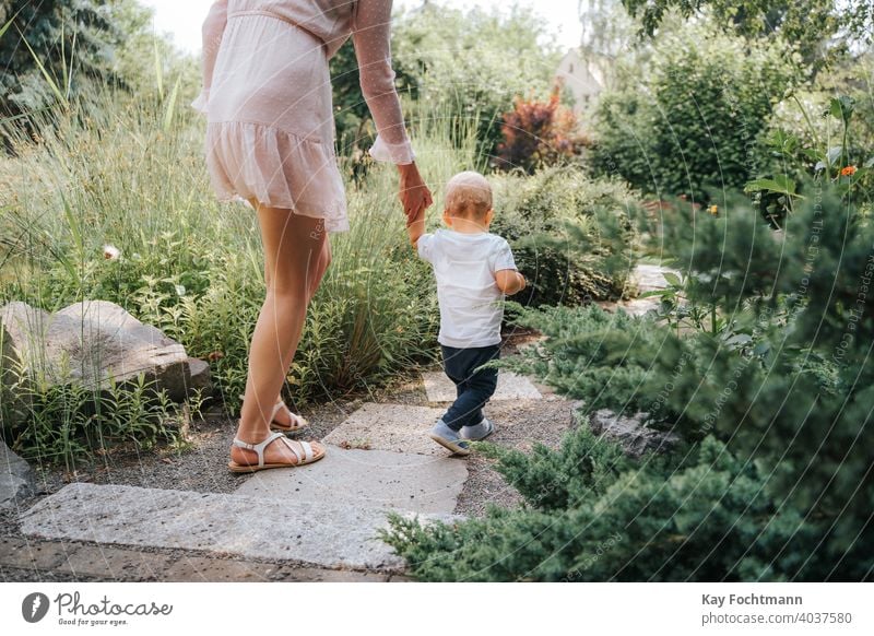 toddler learning to walk with the help of his mother outdoors adorable baby bonding boy child childhood crawl crawling cute emotions explore exploring