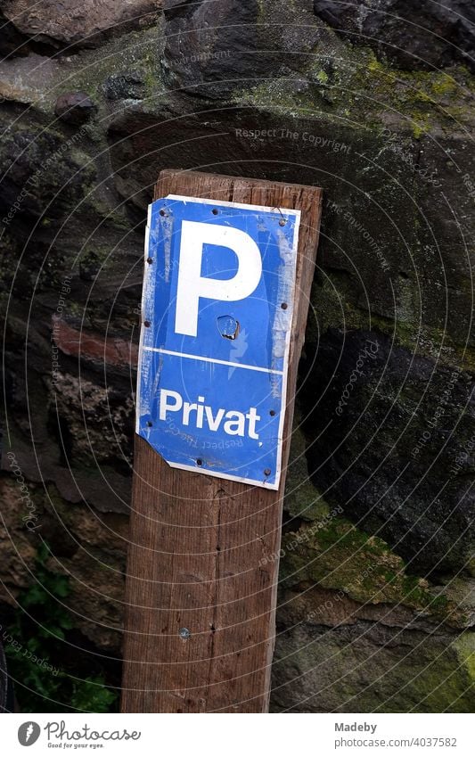 Dilapidated parking lot sign in the rain in front of old masonry made of natural stone in Wettenberg Krofdorf-Gleiberg near Giessen in Hesse, Germany