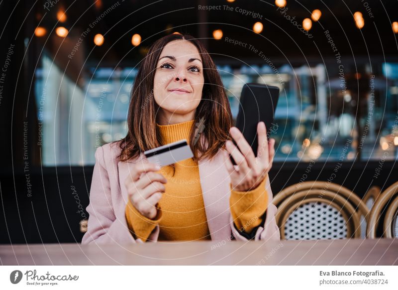 happy caucasian woman in terrace using mobile phone device and credit card for online shopping. Technology and lifestyle concept terrace outdoors yellow sunset