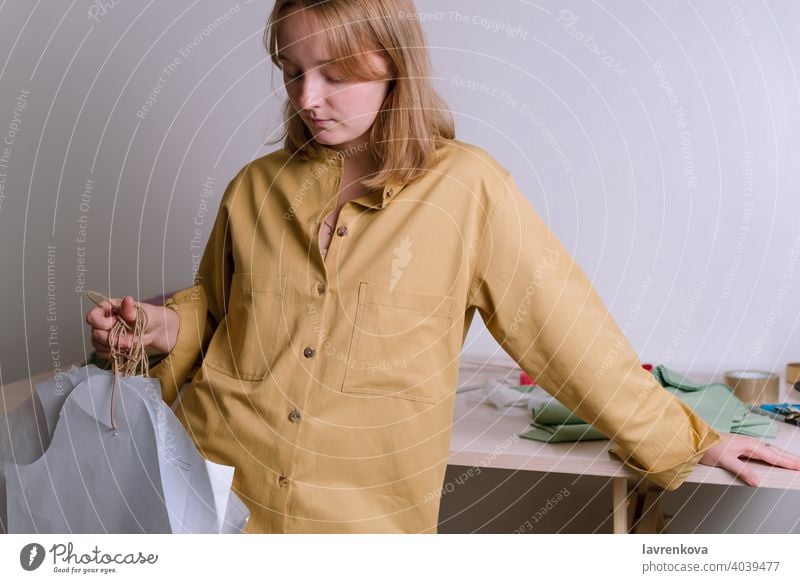 Female in yellow shirt holding paper dress patterns in her workshop tailor craft dressmaker fashion clothing occupation handmade designer textile atelier