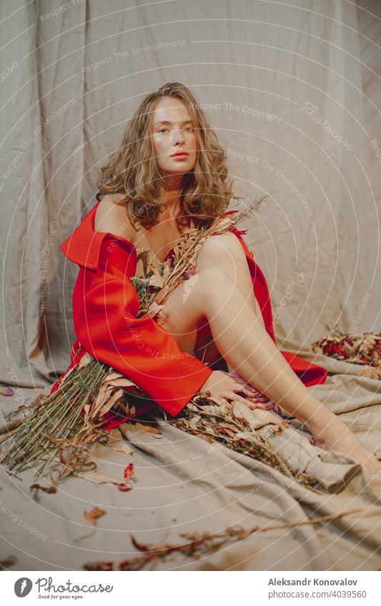 Young redhead woman sit on grey linen fabric under orange coat with flowers and rowan berries beauty Red Orange Hair Freckles Naked Young woman Flower Berries