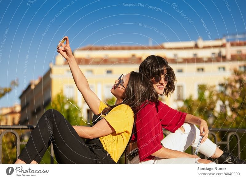 Two teenager girls sitting and taking selfie. madrid young people friendship lifestyle beautiful fun happy together leisure woman smiling teens cheerful female