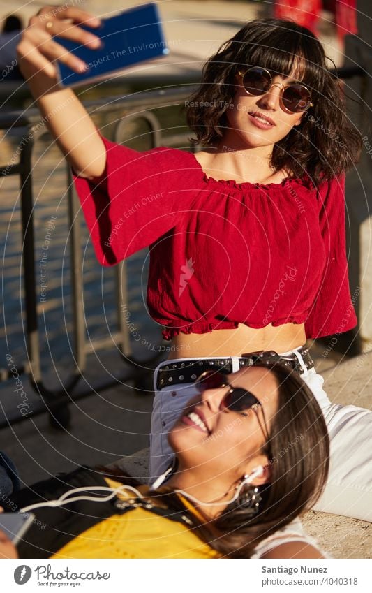 Two teenager girls sitting taking a selfie. madrid young people friendship lifestyle beautiful fun happy together leisure woman smiling teens cheerful female