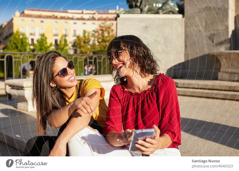 Two teenager girls sitting and laughing madrid young people friendship lifestyle beautiful fun happy together leisure woman smiling teens cheerful female youth