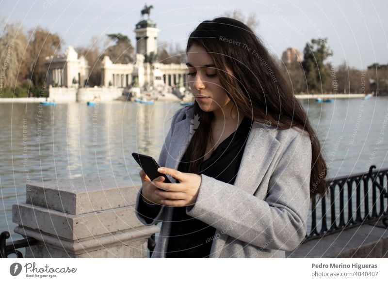 Woman looking her phone in a park. playing girl hand holding application street lady walking social woman outside life watching entrepreneur text message online