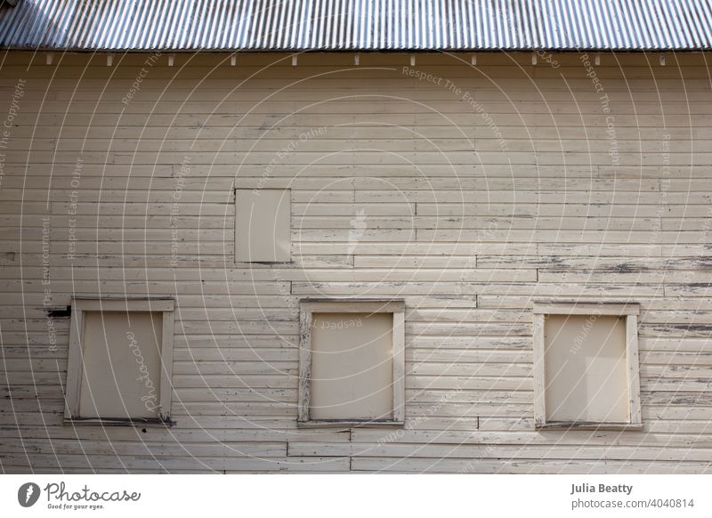 Old wood barn outbuilding with a row of boarded up windows and a metal corrugated roof white wash farmer's market barn wood outdoors summer outside happy