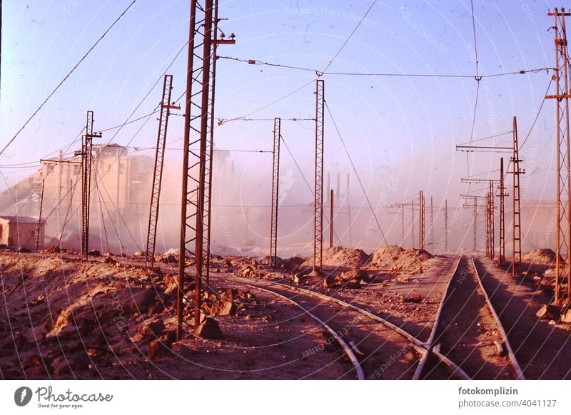 Railway tracks on factory site in the desert railway tracks rails Factory Factory site Industrial area Industry Electricity Transmission lines Cable Technology