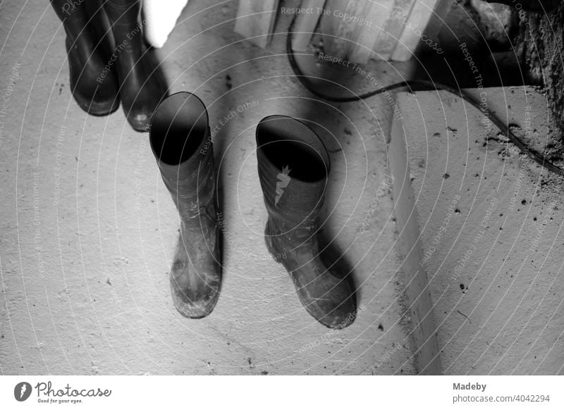 Rubber boots on stone floor in the cellar of an old farmhouse in Rudersau near Rottenbuch in the district of Weilheim-Schongau in Upper Bavaria, photographed in neo-realistic black and white