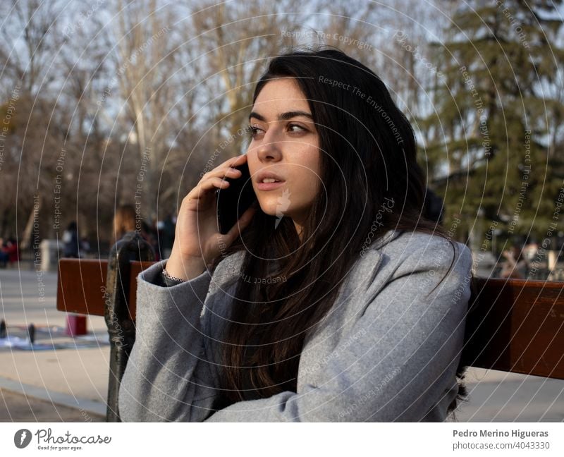 Woman sitting on a bench talking with her mobile in a park. person attendance smartphone walking conversation trouble news complaint service claim unhappy