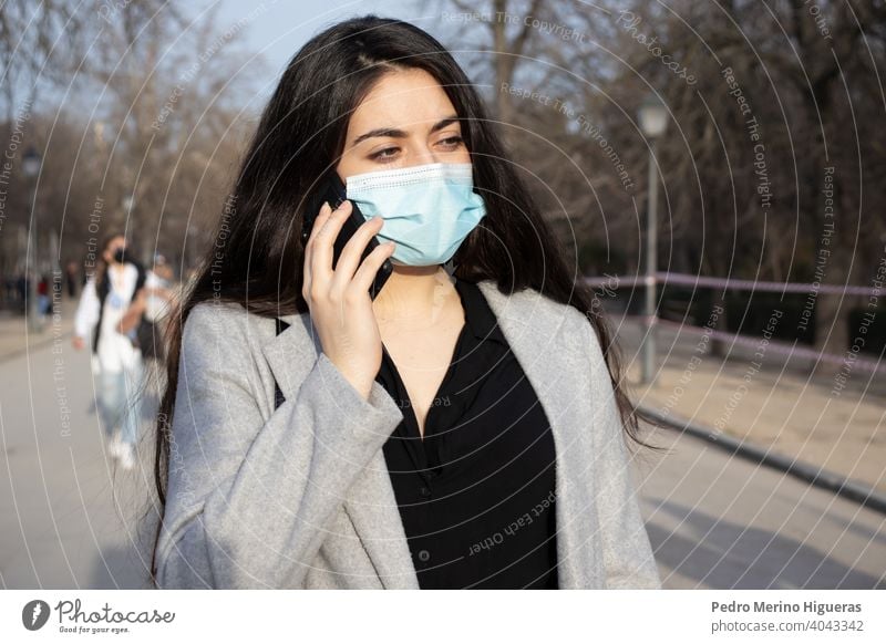 Woman with face mask talking with her mobile in a park. person adult pollution phone air care dust pandemic caucasian epidemic detail wearing allergy mouth