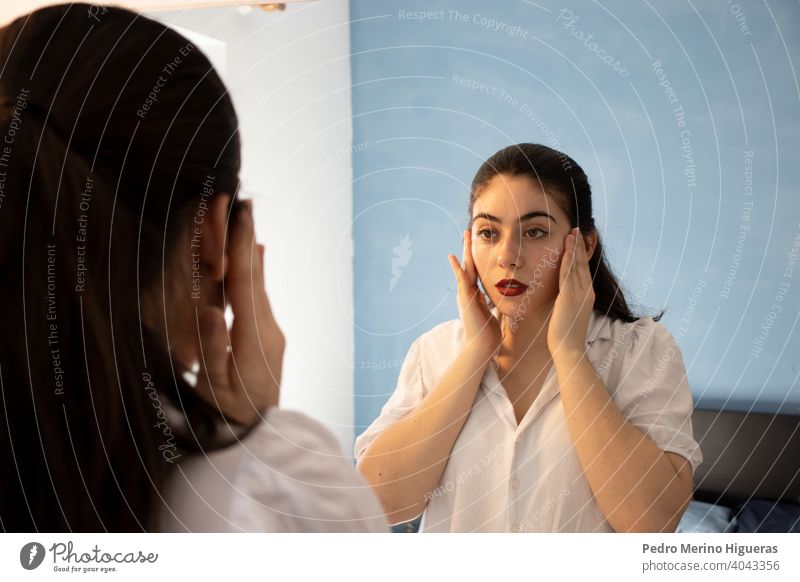 Beautiful woman cleaning her face in front of a mirror fresh constructed honed white touch make-up beauty cleansing hand eye sexy isolated health youth spa view