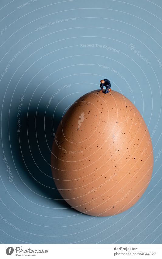 Easter under corona conditions: Miniature figures squats lonely on a huge Easter egg Bacterium covid-19 Virus carrier coronavirus Virus infection